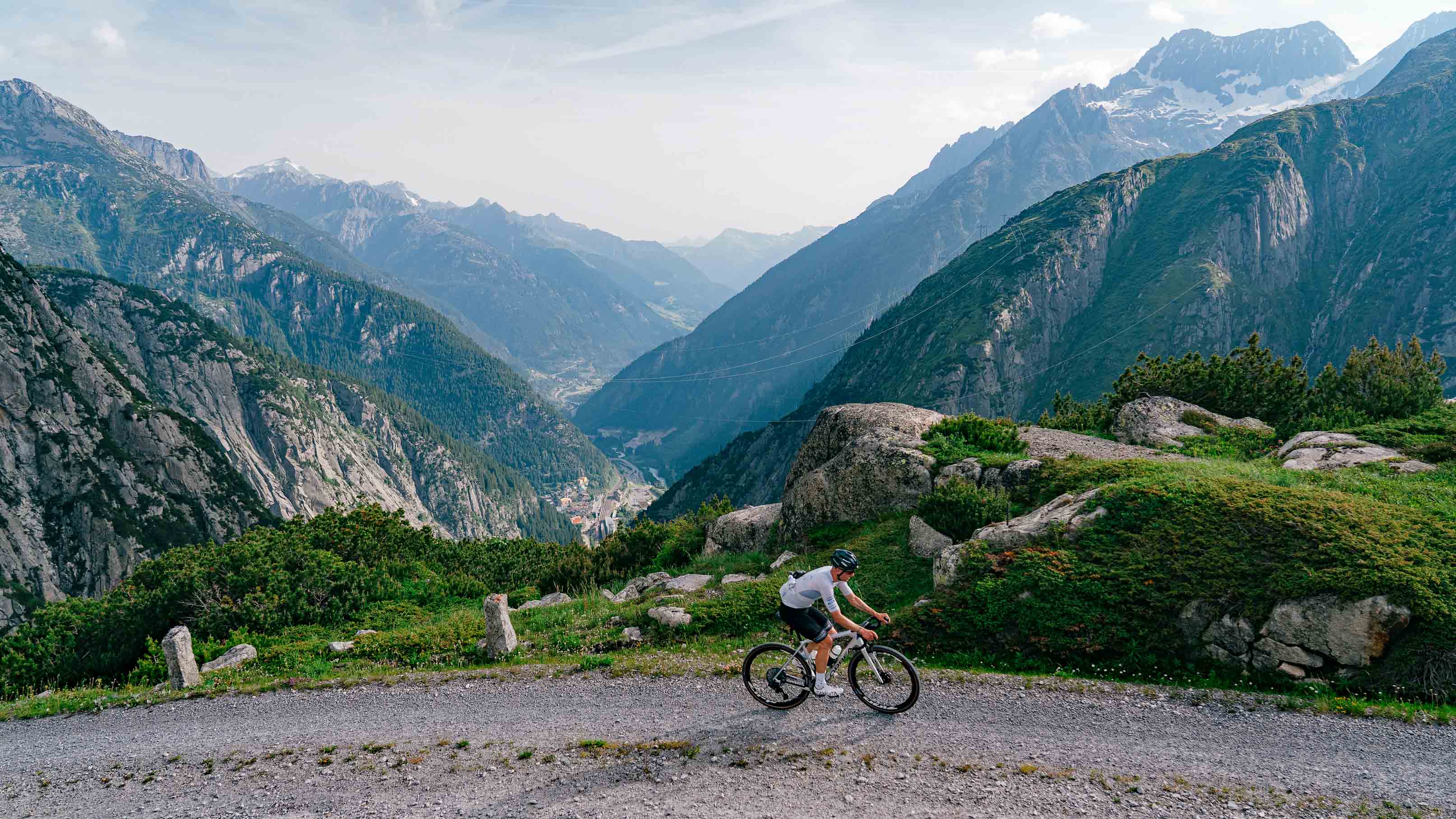 Gravelfahrer auf einer Schotterstrasse hoch über einem Alpental in der Region Andermatt